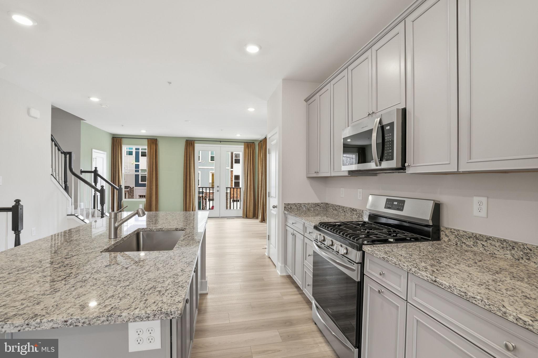 1810 Betterton Road Essex, MD 21221 - Photo 14 of 34 a kitchen with stainless steel appliances granite countertop a stove top oven a sink a refrigerator and white cabinets with wooden floor