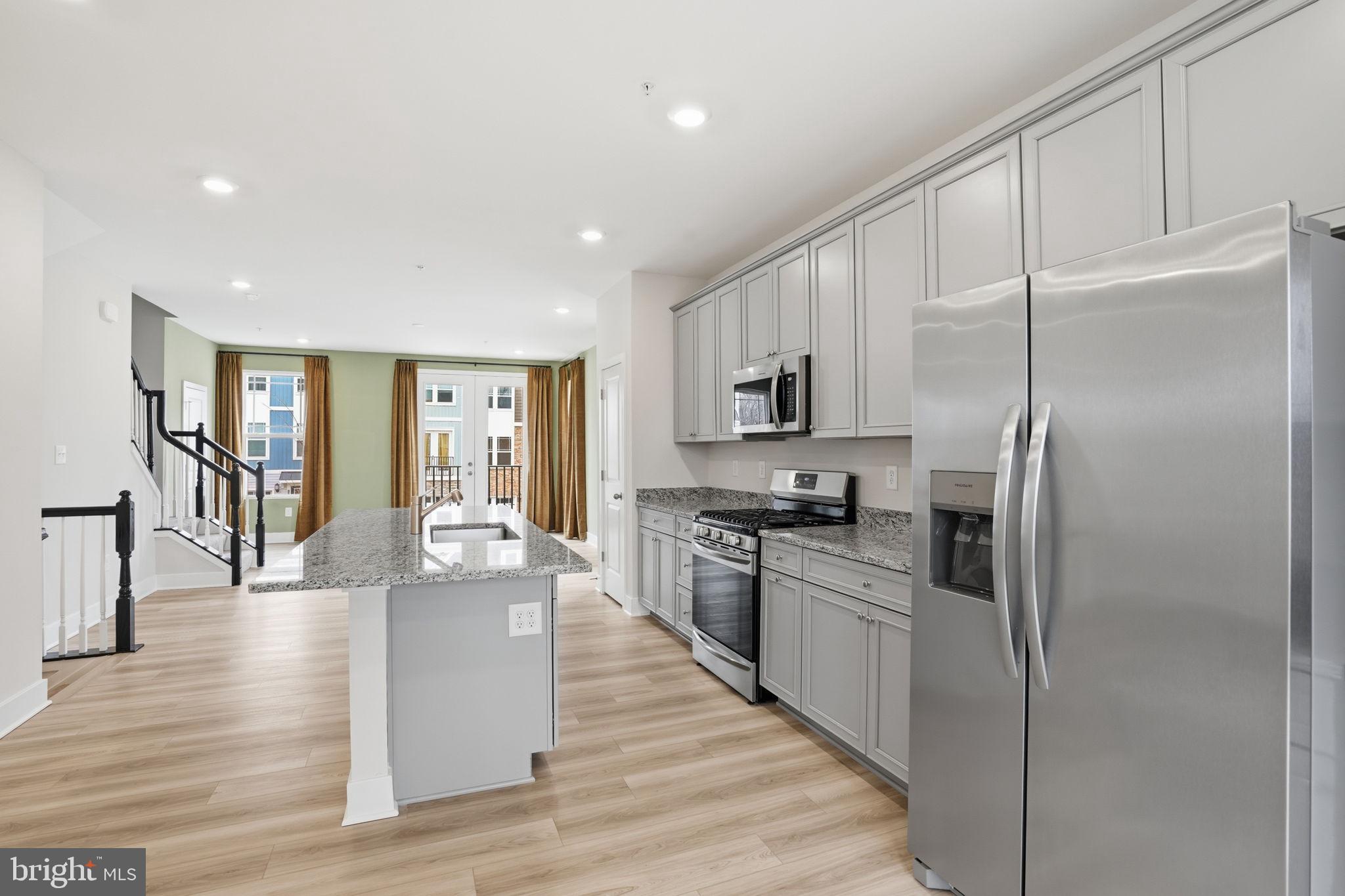 1810 Betterton Road Essex, MD 21221 - Photo 15 of 34 a kitchen with stainless steel appliances granite countertop a refrigerator a stove oven and white cabinets with wooden floors