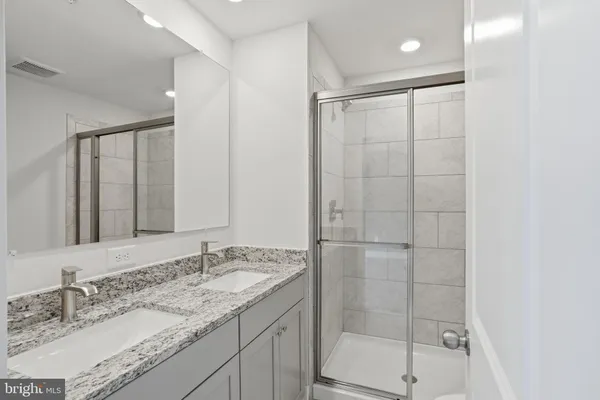 a bathroom with a granite countertop sink a mirror and shower