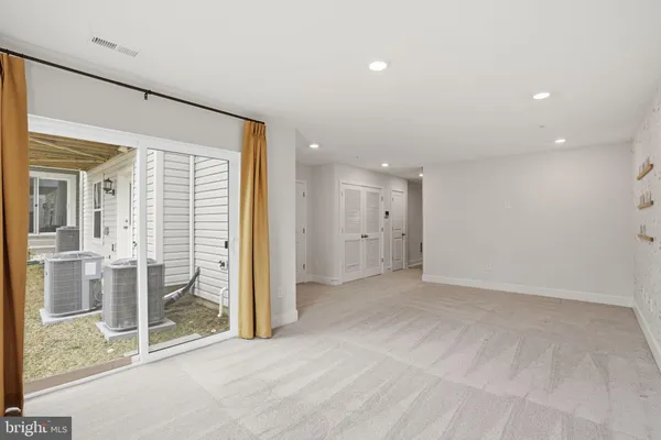 en empty room with sliding glass door and chandelier fan