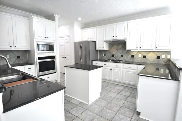 a kitchen with granite countertop a sink a stove a refrigerator and cabinets