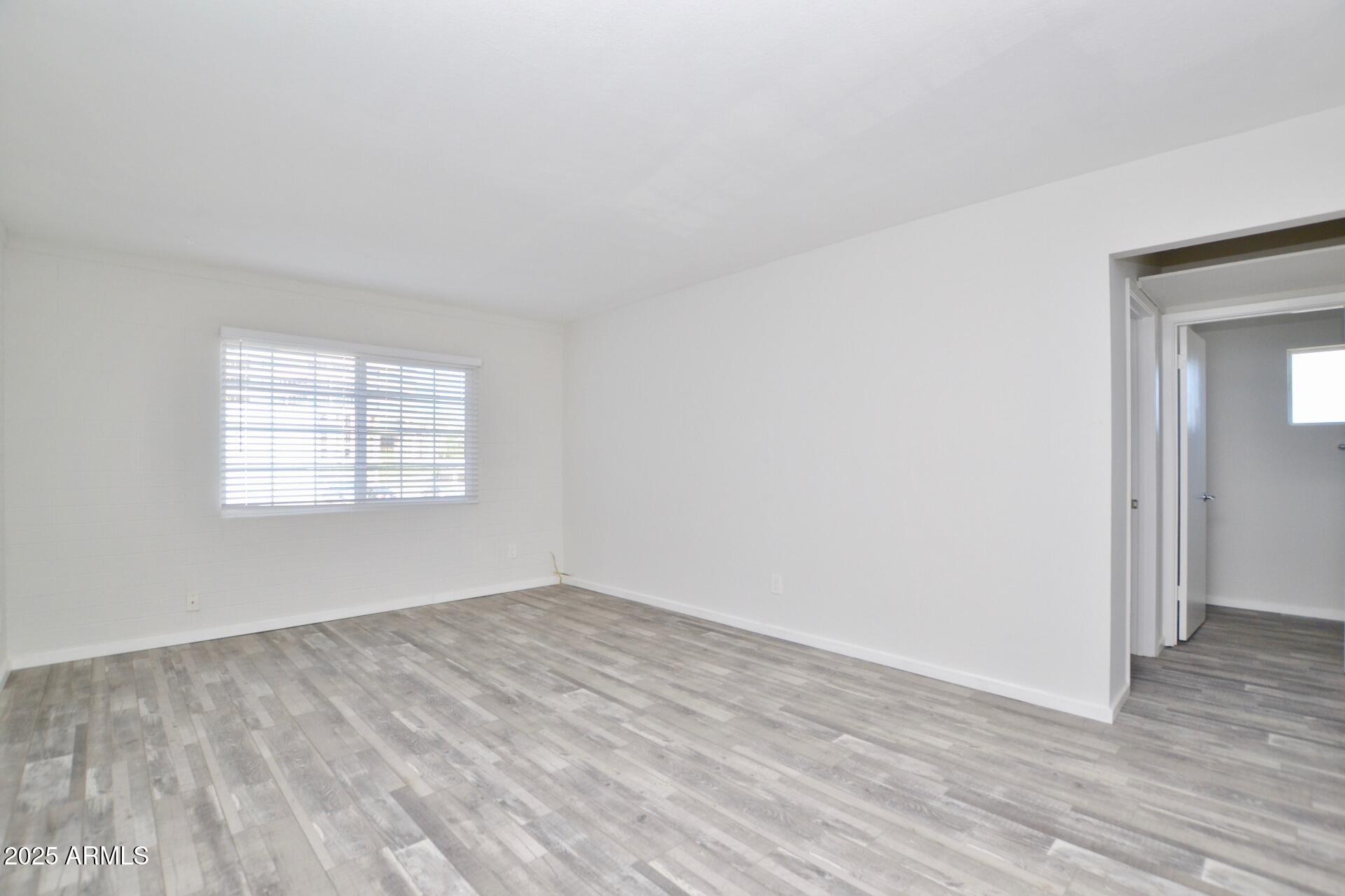 44 East Roanoke Avenue, Unit 8 Phoenix, AZ 85012 - Photo 4 of 11 an empty room with wooden floor and windows