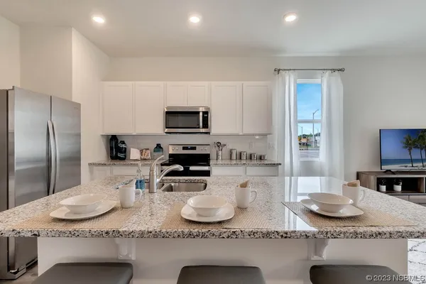 a kitchen with kitchen island granite countertop a sink a counter space and stainless steel appliances