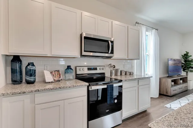 a kitchen with granite countertop white cabinets stainless steel appliances dining table and chairs