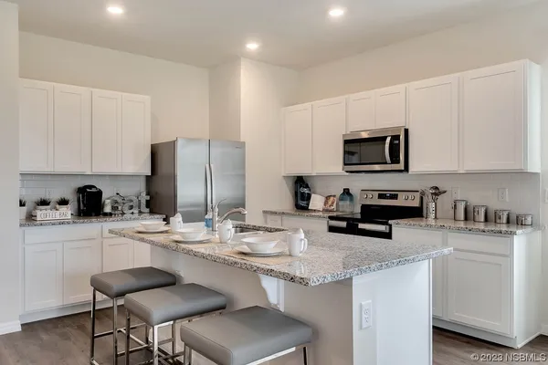 a kitchen with stainless steel appliances a stove a sink a microwave a refrigerator and cabinets