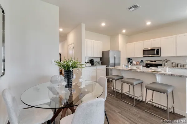 a kitchen with stainless steel appliances kitchen island granite countertop a stove a sink a microwave a dining table and chairs