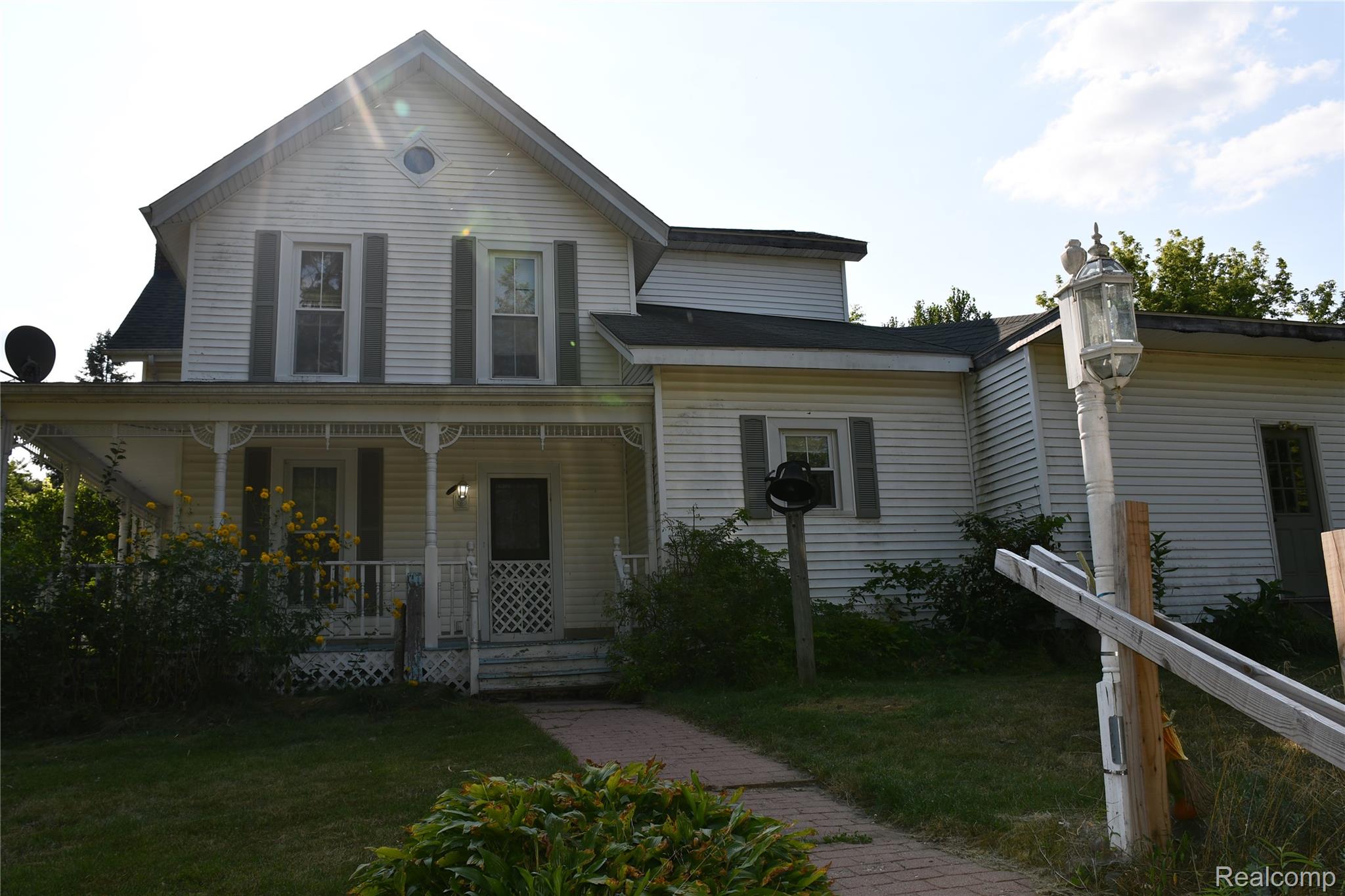 5245 East Clyde Road Howell, MI 48855 - Photo 4 of 28 Traditional siding exterior with a covered front porch, decorative porch columns, and a brick pathway