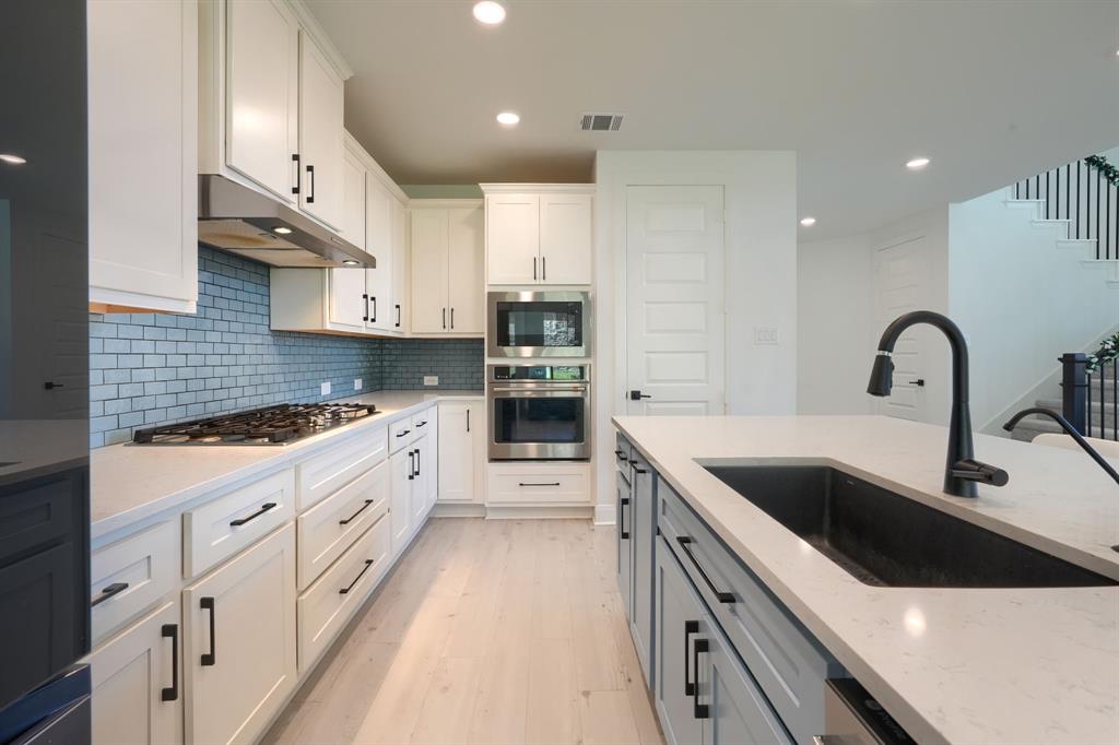 1348 Bay Laurel Road Fate, TX 75087 - Photo 11 of 35 a kitchen with granite countertop a sink and white cabinets