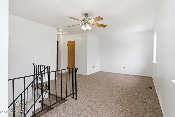 an empty room with windows and fan