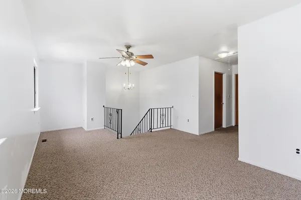 a view of an empty room with a chandelier fan