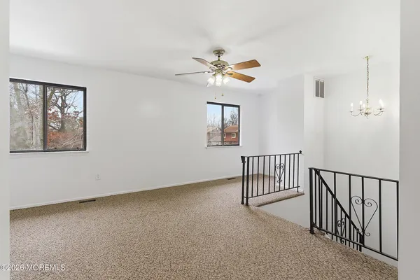 an empty room with windows and fan