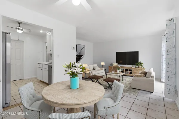 a living room with furniture a flat screen tv and a refrigerator