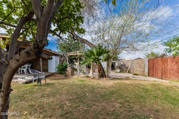 a view of a backyard with a table and chairs under a large tree