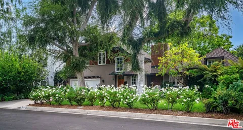 a view of a brick house with a yard and plants