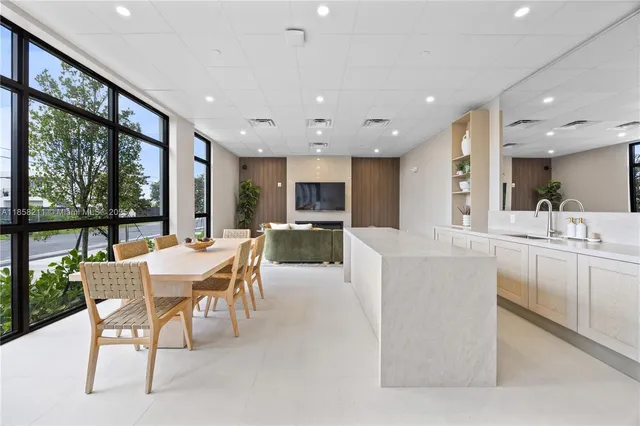 a dining hall with stainless steel appliances a dining table wooden floor and a large window