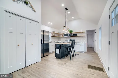 a kitchen with stainless steel appliances kitchen island granite countertop a table chairs sink and cabinets