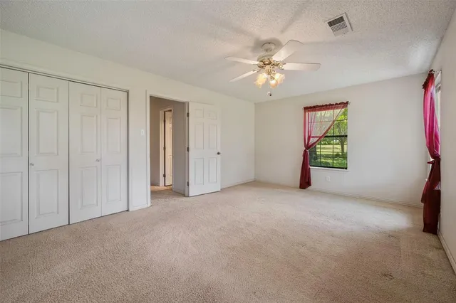 an empty room with windows and fan