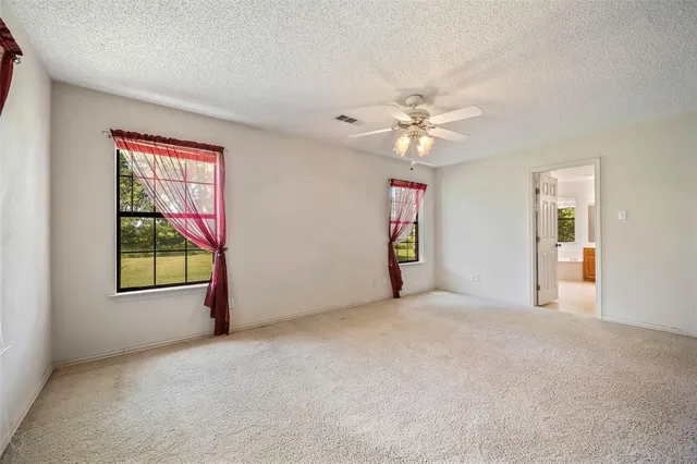 an empty room with windows and chandelier fan