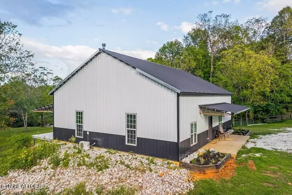a view of a white house next to a yard with big trees