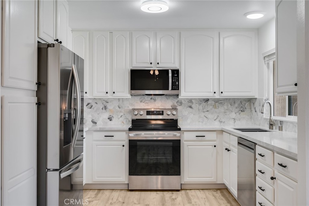 34112 Selva Road, Unit 329 Dana Point, CA 92629 - Photo 11 of 34 a kitchen with stainless steel appliances white cabinets and a stove a refrigerator with wooden floor
