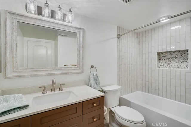 a bathroom with a sink vanity mirror bathtub shower and toilet