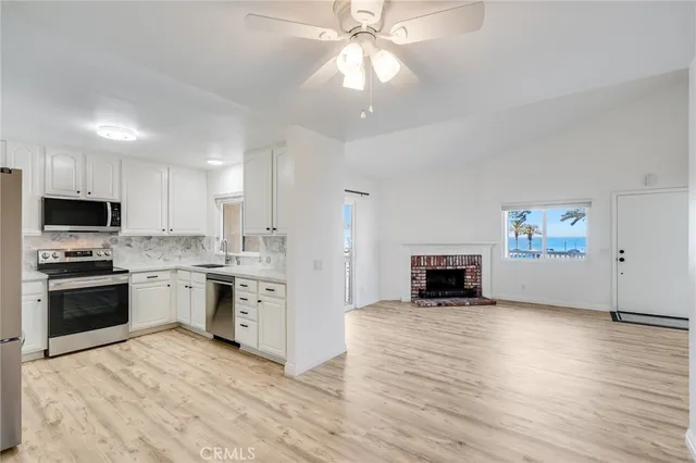 a large kitchen with granite countertop a stove top oven a sink dishwasher and a fireplace with wooden floor