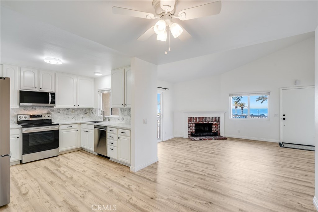 34112 Selva Road, Unit 329 Dana Point, CA 92629 - Photo 6 of 34 a large kitchen with granite countertop a stove top oven a sink dishwasher and a fireplace with wooden floor