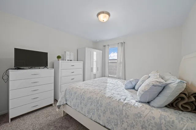 a bedroom with a bed and a flat tv screen on dresser