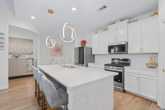 a kitchen with stainless steel appliances a stove a sink cabinets and wooden floor