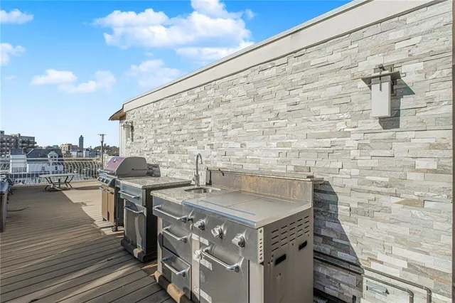 a view of a balcony with wooden floor chairs and a barbeque