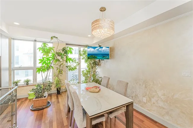 a view of a dining room with furniture a potted plant and wooden floor