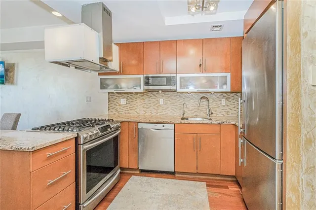 a kitchen with stainless steel appliances granite countertop a stove a sink and a refrigerator