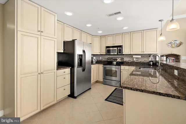 a kitchen with kitchen island granite countertop a sink stainless steel appliances and cabinets