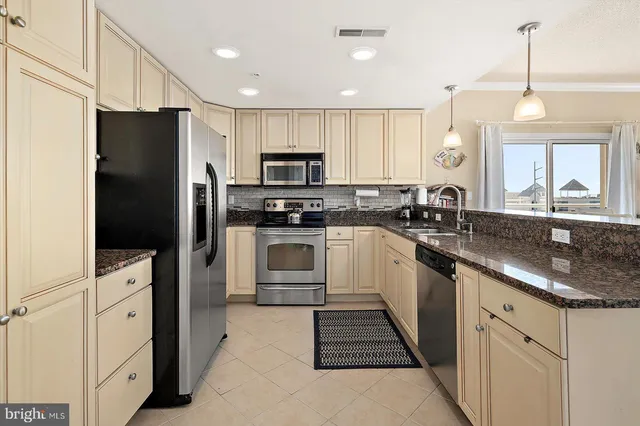 a kitchen with stainless steel appliances granite countertop a stove top oven a sink dishwasher a dining table and chairs with wooden floor