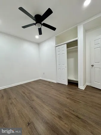 an empty room with wooden floor and a ceiling fan