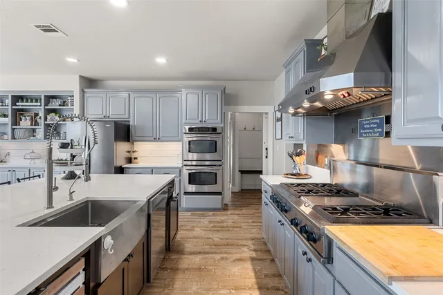 a kitchen with stainless steel appliances granite countertop a stove top oven a sink and a refrigerator