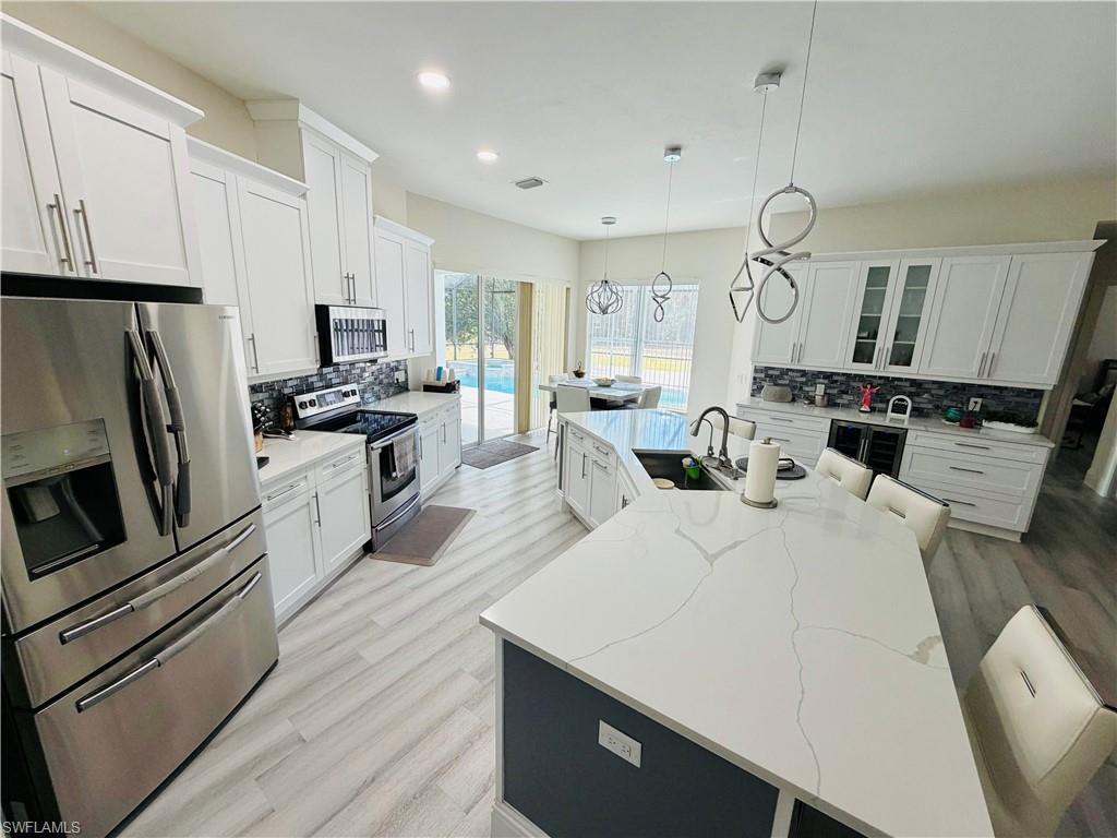 3960 1st Avenue Northwest Naples, FL 34119 - Photo 10 of 25 a large white kitchen with wooden floor