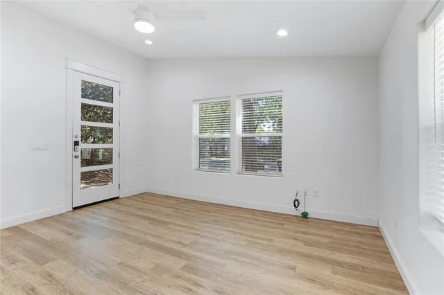 an empty room with wooden floor and windows
