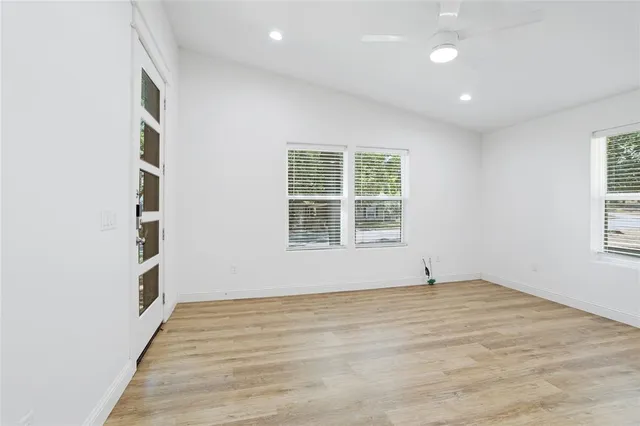 an empty room with wooden floor and windows
