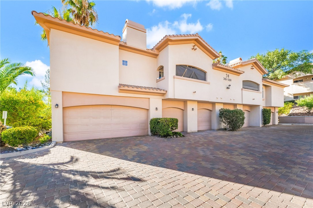 2050 West Warm Springs Road, Unit 2411 Henderson, NV 89014 - Photo 1 of 37 A well-maintained facade features multiple garage entrances and a paver driveway.