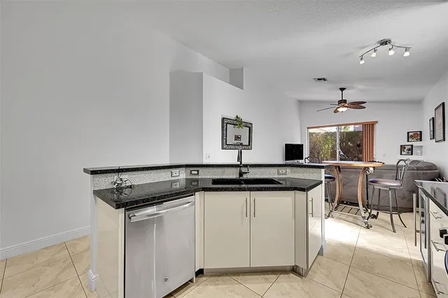 a kitchen with stainless steel appliances granite countertop grey cabinets a stove a sink and dishwasher
