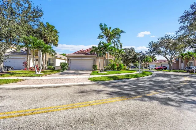 a view of a house with a big yard and palm trees
