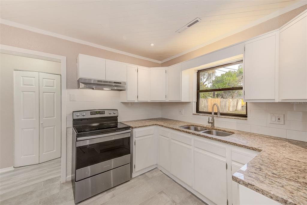 1668 Cleveland Street Clearwater, FL 33755 - Photo 11 of 31 a kitchen with granite countertop a sink cabinets and stainless steel appliances