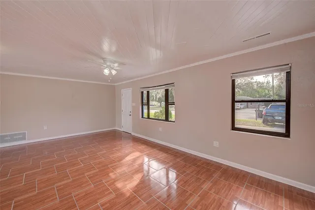 a view of an empty room with window and wooden floor