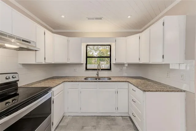 a kitchen with granite countertop white cabinets and white appliances