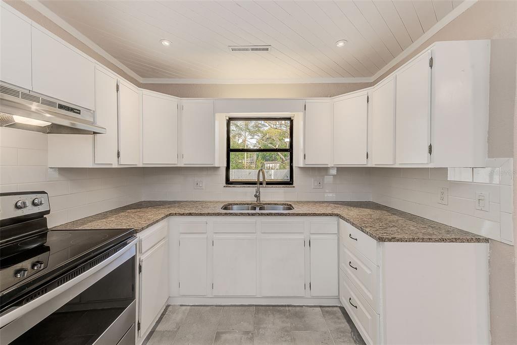 1668 Cleveland Street Clearwater, FL 33755 - Photo 10 of 31 a kitchen with granite countertop white cabinets and white appliances