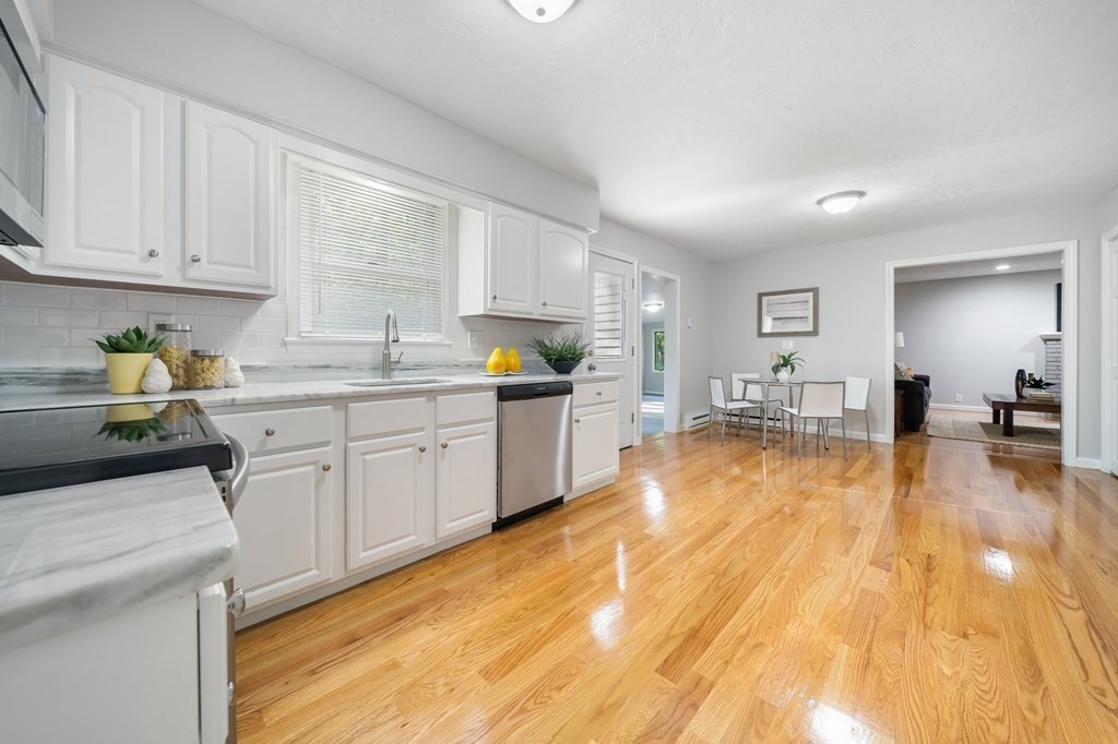 35 Old Village Road Sturbridge, MA 01566 - Photo 4 of 39 a large white kitchen with wooden floors and stainless steel appliances