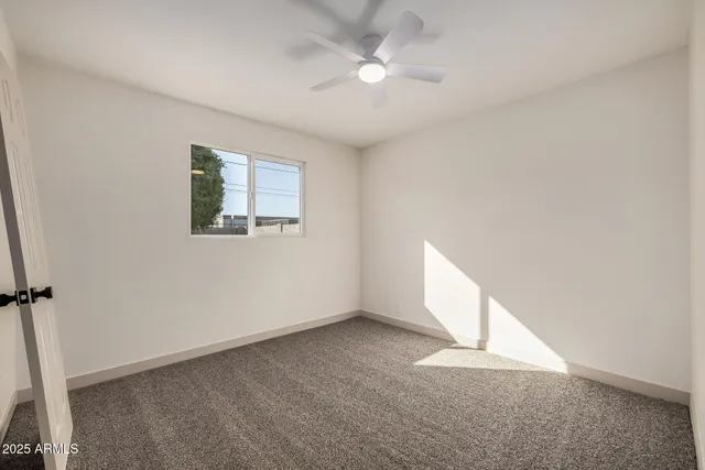 an empty room with a ceiling fan and a window