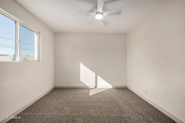 an empty room with a ceiling fan and window