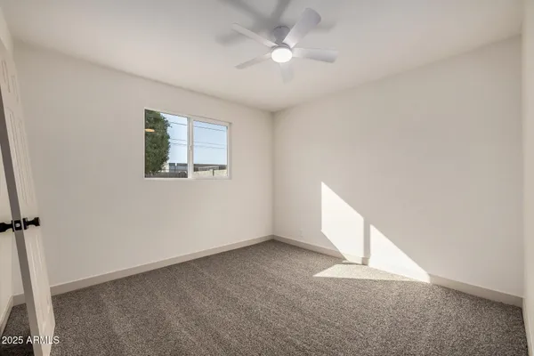 an empty room with a ceiling fan and a window